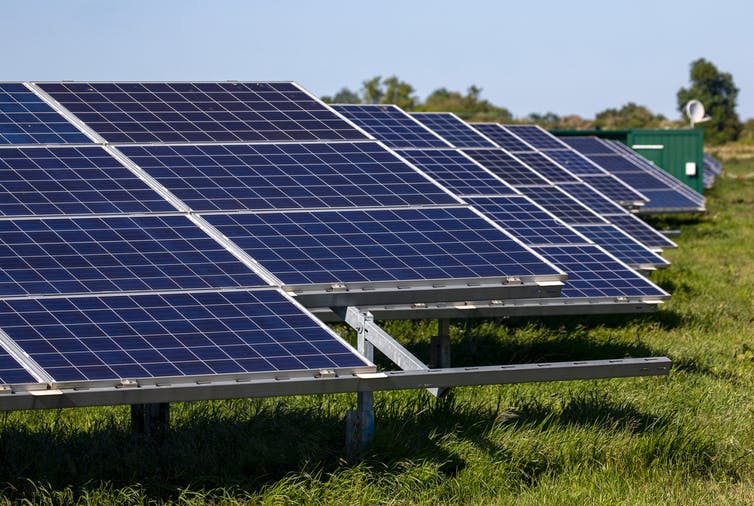 Rows of solar panel arrays in a field on a sunny day.