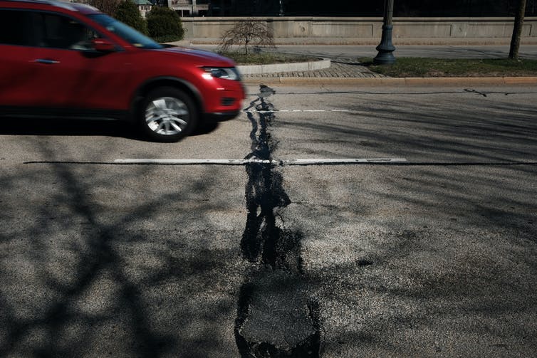 A car drives along a road in need of repair