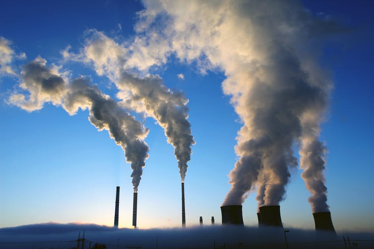 industrial stacks emitting steam to blue sky