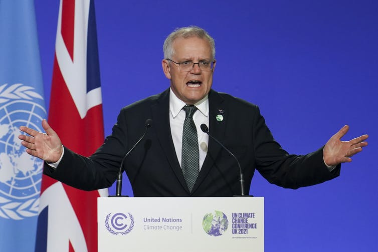 Man in suit gestures as he speaks at COP26 climate summit