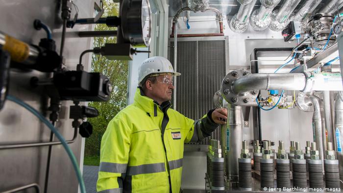 A worker in a yellow hi-vis jacket stands inside a power-to-gas plant in Hamburg