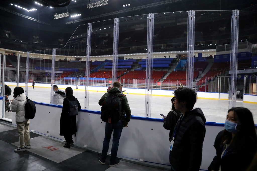 Reporters and staff members from the committee of Beijing 2022 Winter Olympics, stand outside a ground which will be turned into an ice rink at the Wukesong Sports Centre, a venue for ice hockey competitions during the Games, during an organized media tour, China, Dec. 9, 2021.