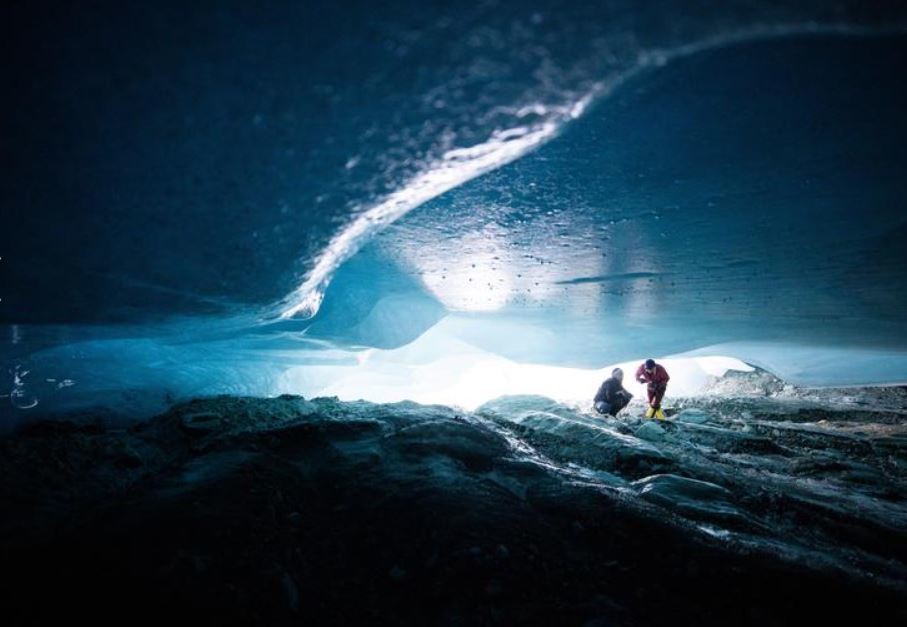 Glaciologists exploring the ice cave which will eventually collapse the glacier above as warmer air rushes in.