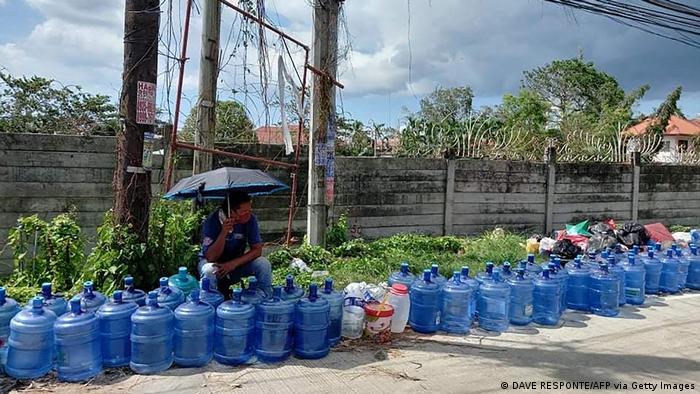 Residents with their water plastic containers queue up to fetch water along a road in Tagbilaran City