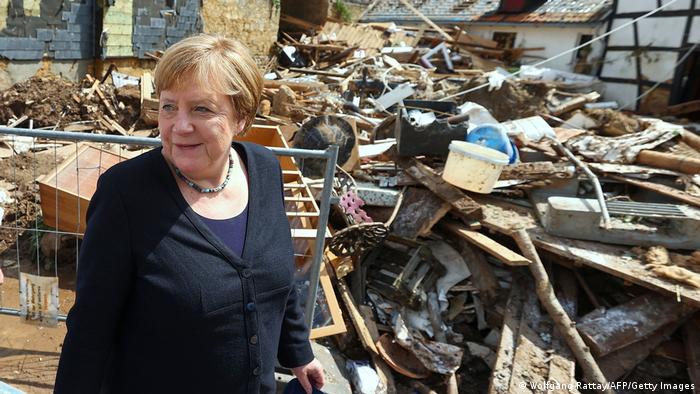 Merkel standing next to a pile of debris