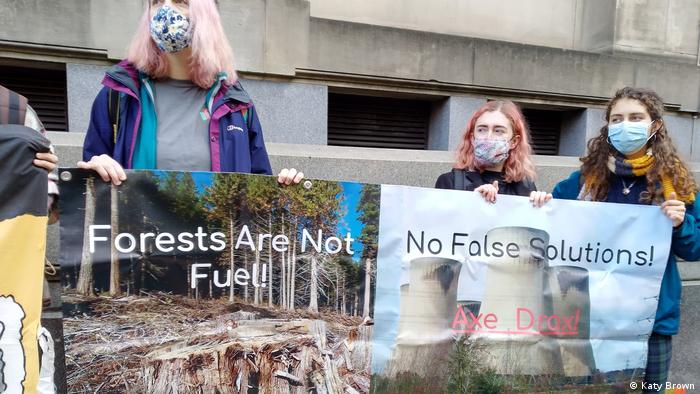 Young women wearing masks hold up protest signs 