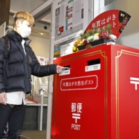 A person drops a New Year's greeting card into a post box at the central Tokyo post office on Dec. 15, as post offices begin accepting the cards for delivery on Jan. 1. | KYODO
