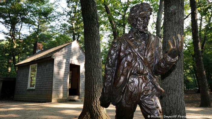 A statue of philosopher Henry David Thoreau in front of a re-creation of his cabin at Walden Pond