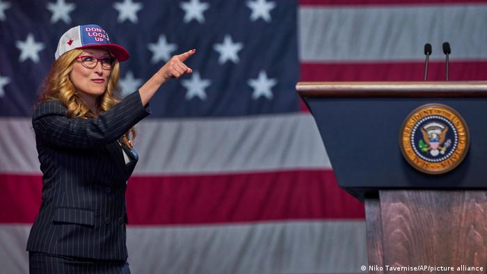 A woman in a put points in front of the American flag