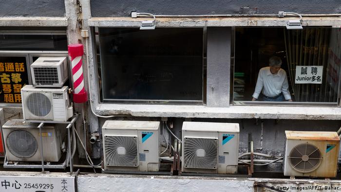 Air conditioning units are seen as a man looks out of a window of a mixed business-residential building in Hong Kong's Central district