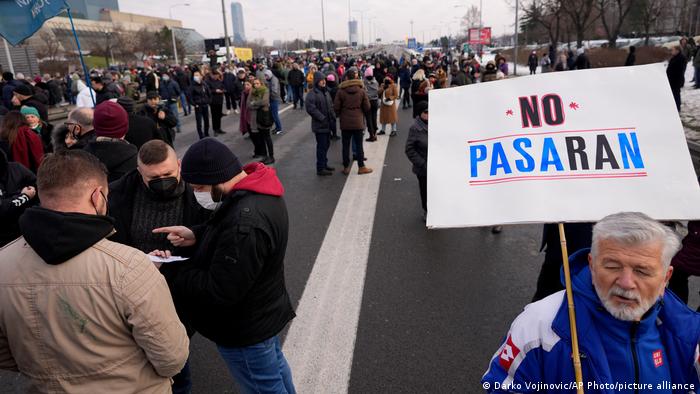 A environmental demonstrator holds a banner reading: No Pasaran as a highway is blocked, during a protest in Belgrade