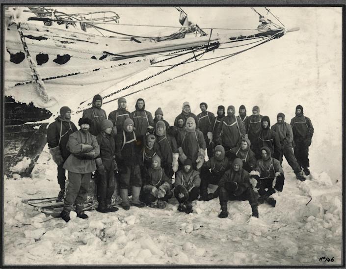 Officers and crew of the 'Endurance' - the shore party group pose under the bow of the 'Endurance' at Weddell Sea Base during the Imperial Trans-Antarctic Expedition, 1914-17, led by Ernest Shackleton. / Credit: SPRI University of Cambridge / Getty Images