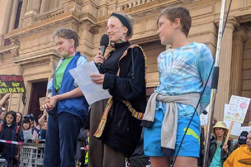 A teenager stands in the middle of a stage as part of climate rally