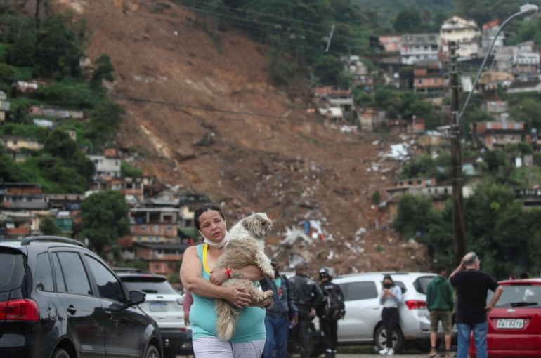 A woman carries her dog at a shelter for people displaced by landslides in Brazil