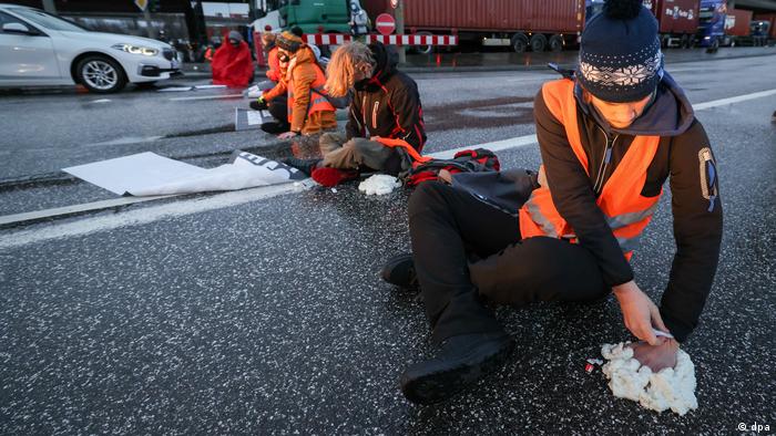 Climate activists blocking a busy road in Hamburg, gluing their hands to the pavement 