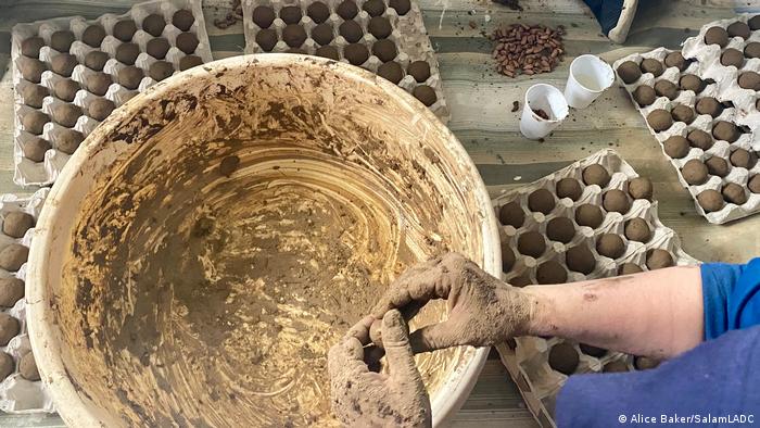 A woman uses her hands to form seed bombs from seeds, soil and clay