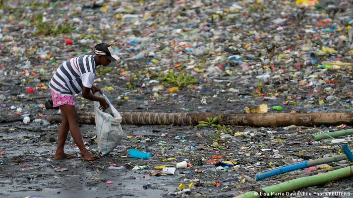 A child in the Philippines collecting plastic rubbish from a river