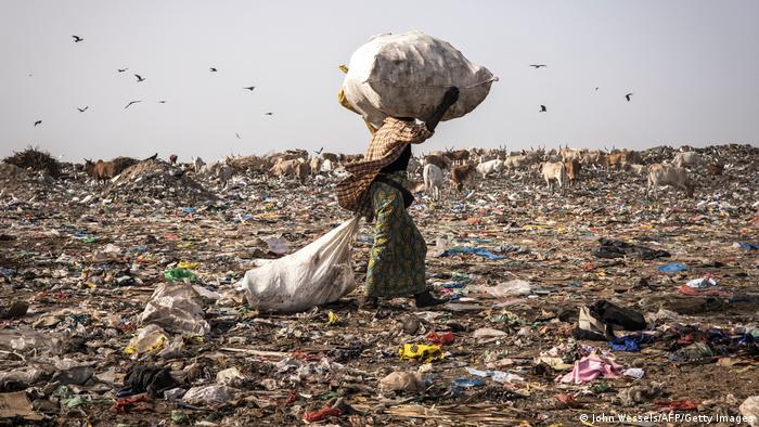 A waste picker walks with a load of recyclable waste on her head in the Mbeubeuss rubbish dump in Dakar.