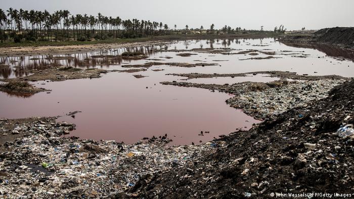 A lake has turned red from pollution is pictured on the outskirts of the Mbeubeuss rubbish dump.
