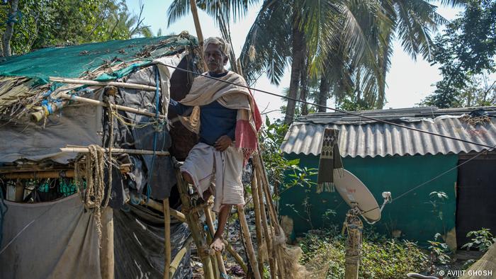 A man standing an a ladder to a makeshift hut 