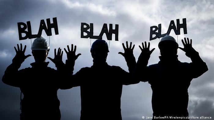 Three activists dressed as miners and the words blah blah blah
