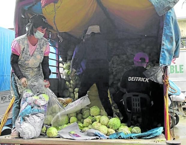 TRADERS HUB Workers at the vegetable trading post in La Trinidad, Benguet, unload vegetables coming from other areas in the Cordillera in this April 3 photo. Local farmers continue to fight the unabated vegetable smuggling in the country. ALLAN MACATUNO