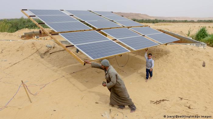 A man and his child in front of the solar panels in the desert