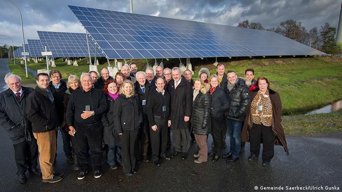 Group photo in the city of Saerbeck with visitors from the US in front of a solar panel park
