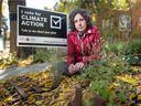 Amy Snider sits next to a climate-themed lawn sign at her home in Regina, Saskatchewan on Oct. 8, 2020. 