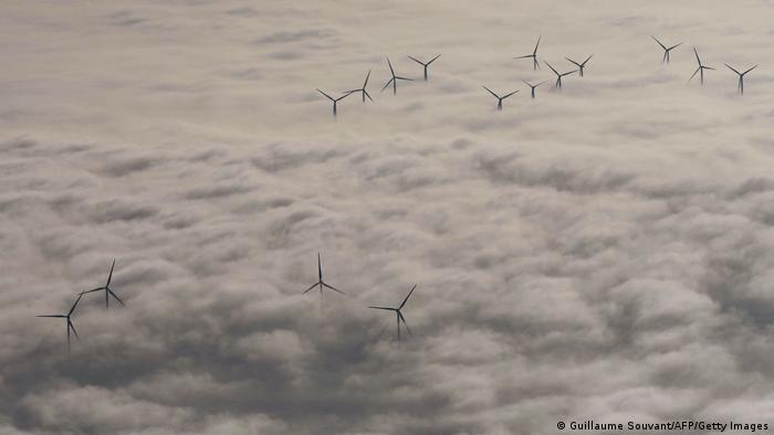 Wind turbines poke out from above a blanket of cloud cover