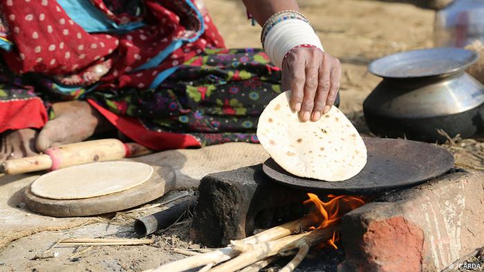A woman cooks on a simple outdoor stove