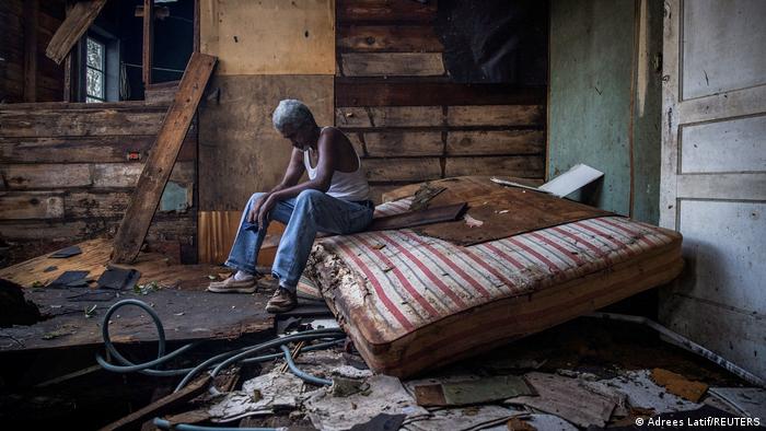 A man sits in his house destroyed by Hurricane Ida.