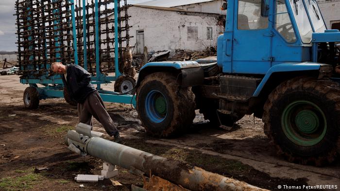 A farm worker in Ukraine looking at a rocket by his tractor