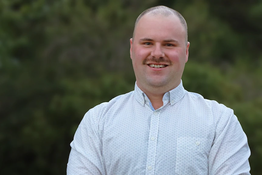 A man wearing a collared shirt posing for a photograph.