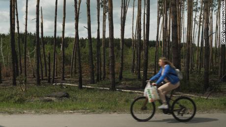 A cyclist passes a damaged section of a forest in Irpin.