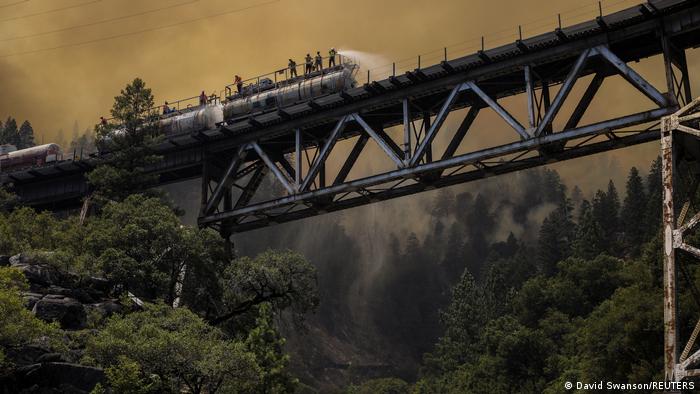 Firefighters battle the wildfire from a bridge in the Plumas National Forest in California.