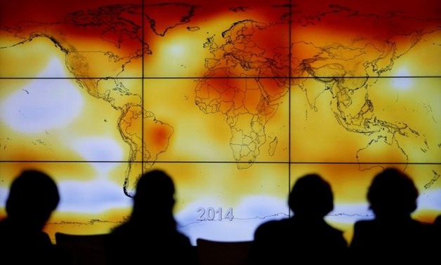 Participants are seen in silhouette as they look at a screen showing a world map with climate anomalies during World Climate Change Conference 2015 (COP21) at Le Bourget, near Paris, France, December 8. REUTERS