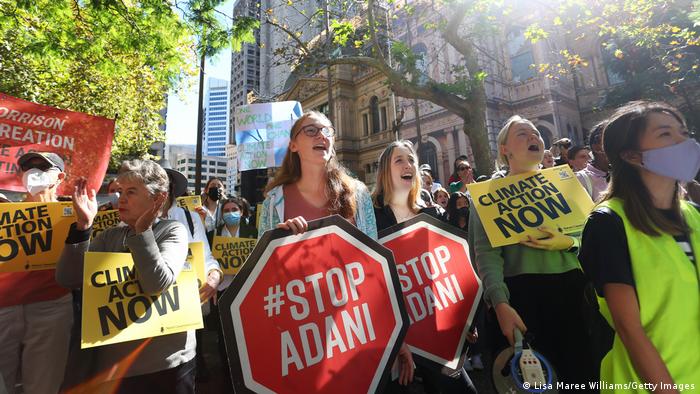 Climate protestors holding signs saying: climate action now and stop adani